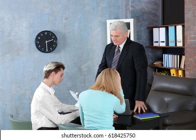 Young Woman And Son Meeting With Teacher At School