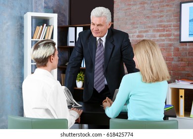 Young Woman And Son Meeting With Teacher At School