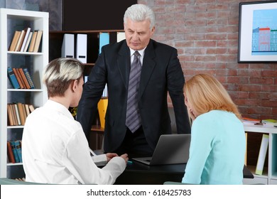 Young Woman And Son Meeting With Teacher At School