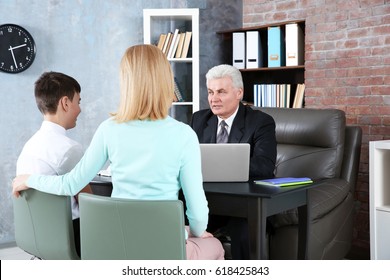 Young Woman And Son Meeting With Teacher At School