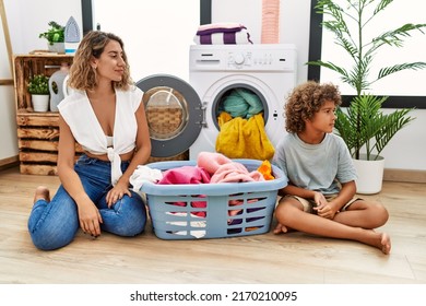 Young Woman And Son Putting Dirty Laundry Into Washing Machine Looking To Side, Relax Profile Pose With Natural Face With Confident Smile. 