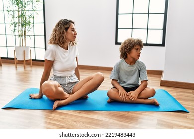 Young Woman And Son Sitting On Training Mat At The Gym Looking To Side, Relax Profile Pose With Natural Face With Confident Smile. 