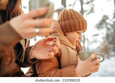 Young woman with a son in winter forest on a picnic drink hot tea - Shutterstock ID 2137850125