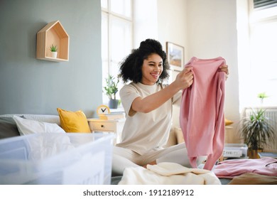 Young woman sorting wardrobe indoors at home, charity donation concept. - Shutterstock ID 1912189912