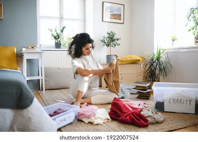 Young woman sorting wardrobe indoors at home, charity donation concept. - Powered by Shutterstock