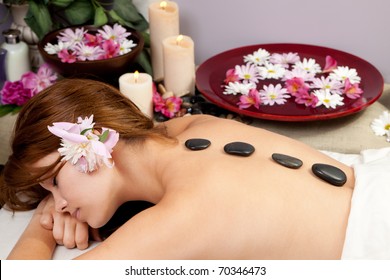 A Young Woman At A Spa Waiting For A Massage With Hot Stones On Her Back.