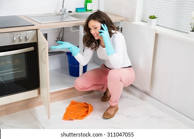 Young Woman Speaking On Mobile Phone In Kitchen