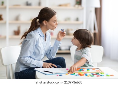 Young woman speech therapist teaching little boy with pronounciation deffects to say sound U during personal training at classroom - Shutterstock ID 2139736683