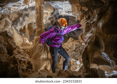 Young woman spelunking inside a cave. Feminism concept. Concept of women's sport.