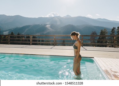 Young woman spending winter or spring vacation in luxury spa resort with swimming pool over alpine mountain landscape - Powered by Shutterstock