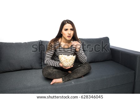 Young woman spends his free time watching TV on the couch munching chips and popcorn