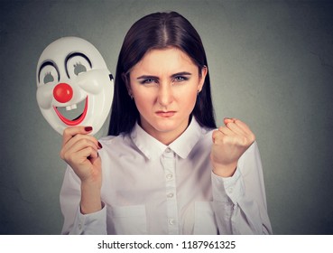 Young Woman With Split Personality Looking Super Angry At Camera While Holding Clown Mask To Hide