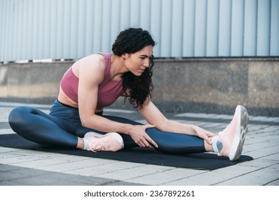 Young woman in sport wear and sneakers shoes stretching legs before going for jog, touching ankle, hamstring. Getting muscles ready for run outside. Prevention injury concept. - Powered by Shutterstock