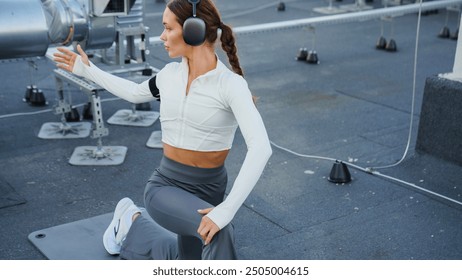 Young woman in sports clothes stretching in low lunge outdoors in residential area - Powered by Shutterstock