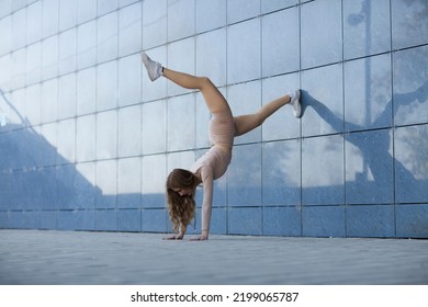 young woman in sports clothing doing handstand yoga asana  while exercising outdoors - Powered by Shutterstock