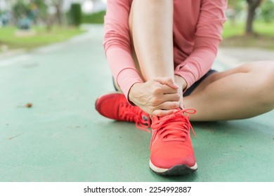 Young woman in sports outfits pink injured her ankle during exercise in the park. Low section of sports girl suffering from flipped ankle while sitting on track during. Accident from exercise concept. - Powered by Shutterstock