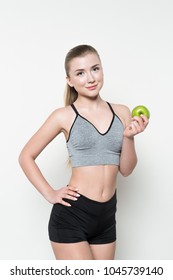 Young woman in sports top holding apple isolated on white