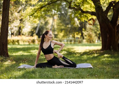  Young woman in sportswear doing leg stretching in the city park. - Shutterstock ID 2141442097