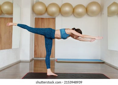 A Young Woman In Sportswear In The Gym Does A Swallow Balance Exercise. The Concept Of A Healthy Lifestyle.Yoga, Fitness, Pilates. High Quality Photo