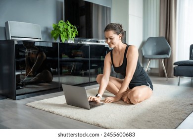 Young woman in sportswear preparing to fitness exercises on mat in living room. Online workout, practicing and meditation at home. High quality photo - Powered by Shutterstock