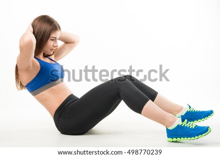 Young woman in sportswear shakes the press on the floor of the house. White background. Healthy lifestyle