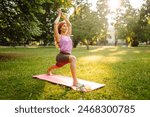 Young woman in sportswear stretching body on fitness mat at public park, doing yoga. Healthy lifestyle, sport. Fitness. Woman doing yoga in morning park.