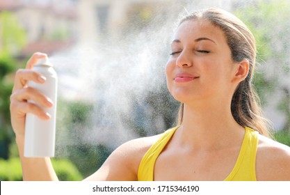 Young woman spraying Thermal Water on her face outside. Thermal water used for skin care, fix makeup, help skin irritation, redness and insect bites. - Powered by Shutterstock