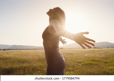 Young woman spreading hands with joy and inspiration facing the sun. She is enjoying serene nature workout vacation outdoors. asian beauty. - Powered by Shutterstock