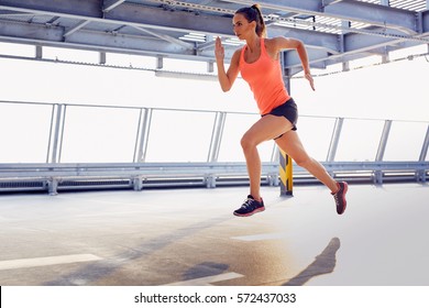 Young Woman Sprinting On Parking Garage During Sunny Summer Day