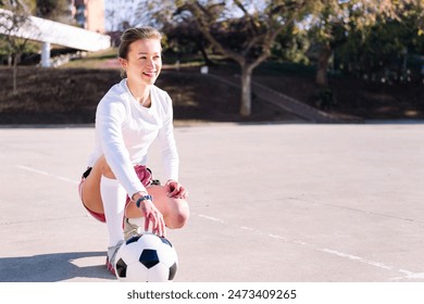 young woman squatting next to a soccer ball - Powered by Shutterstock