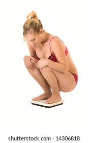 Young woman squatting on bathroom scales, checking weight