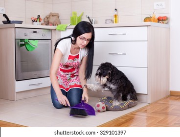 Young woman squatting on knees while cleaning after her dog in the kitchen