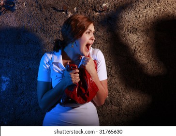 Young woman squealing with horror at the rusty wall. She is scared by someone dangerous.