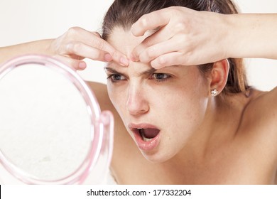 Young Woman Squeeze Her Acne In Front Of The Mirror