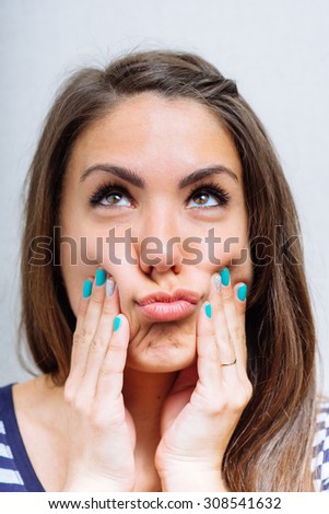 Young woman squeezing her cheeks with her hands