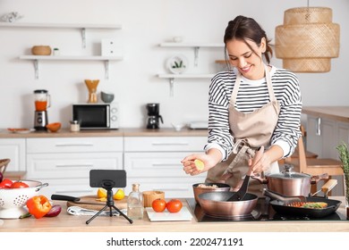 Young woman squeezing lemon into frying pan while following cooking video tutorial in kitchen - Powered by Shutterstock