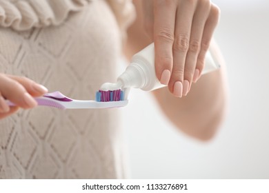 Young Woman Squeezing Toothpaste On Brush, Closeup