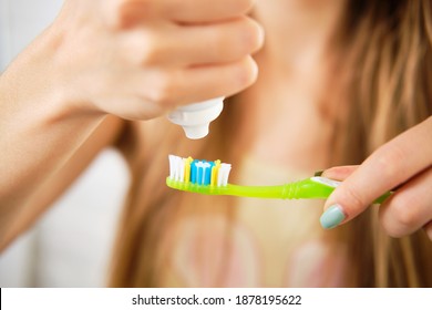 Young Woman Squeezing Toothpaste On Brush, Closeup