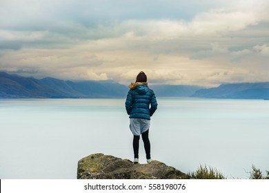 Young woman stand on the rock look at the beautiful Tekapo lake, New Zealand