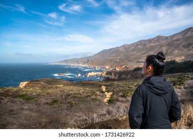 Young Woman Standing Back Admires Panoramic Sea View From Coastal Highway-1, Monterey, CA, USA. Concept Of Solo Traveler.