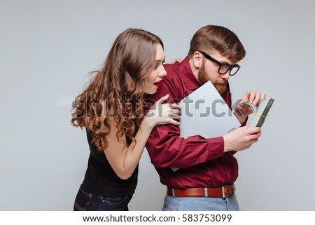 Young Woman standing from back of Male nerd which recounts the money and holding laptop