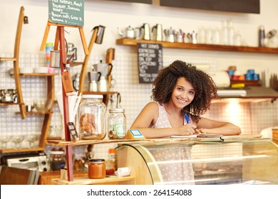 A Young Woman Standing Behind The Counter In A Coffee Shop