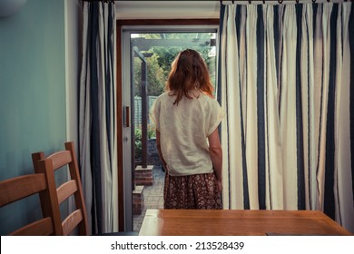 A Young Woman Is Standing By The Curtains Of A Set Of French Doors