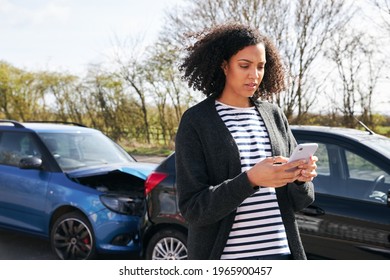 Young woman standing by damaged car after traffic accident reporting incident to insurance company using mobile phone