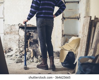 A Young Woman Is Standing By A Fireplace With A Sledge Hammer