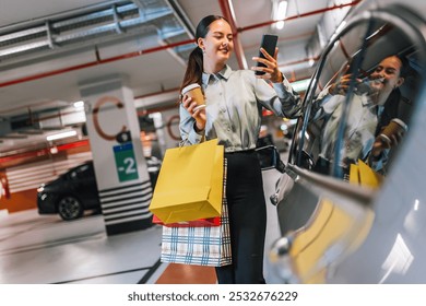 Young woman standing by her car with shopping bags using her phone and drinking coffee. - Powered by Shutterstock