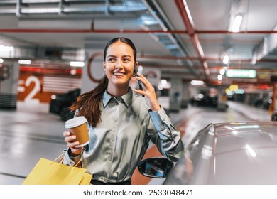 Young woman standing by her car with shopping bags using her phone and drinking coffee. - Powered by Shutterstock