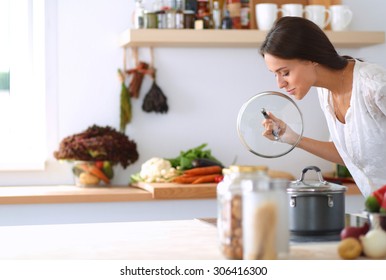 Young woman standing by the stove in the kitchen .
