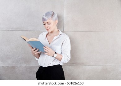 Young Woman Standing By Wall, Reading A Book.