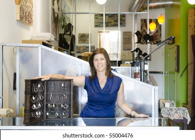 Young Woman Standing With A Display Case Of Jewelry At A Store Counter